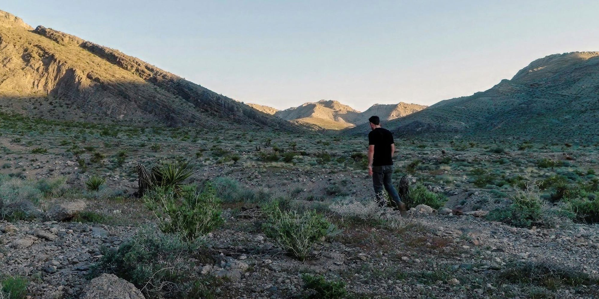 a man walks along a trail in the early morning sunlight