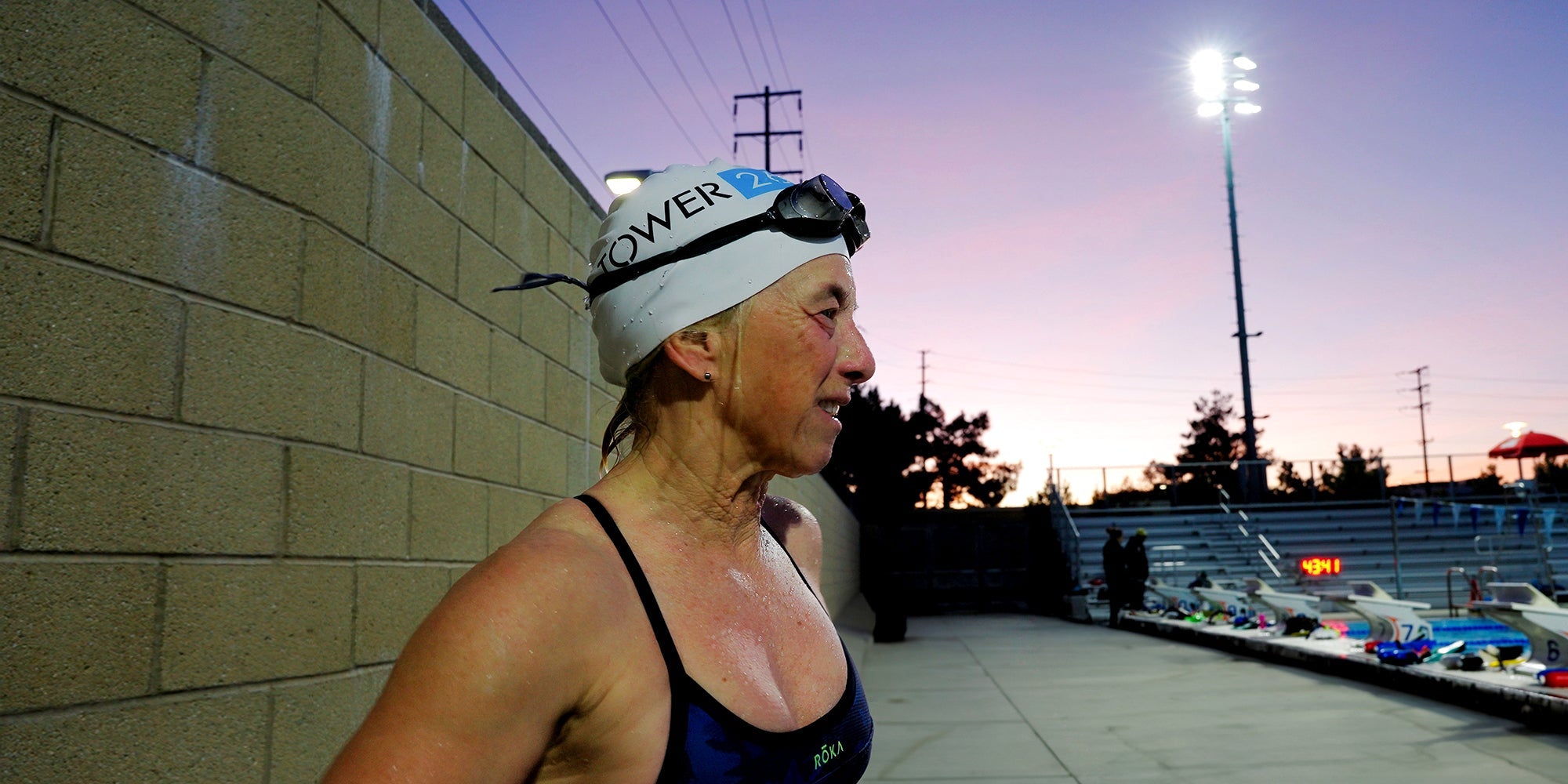 a swimmer stands on pool deck in a Tower 26 swim cap