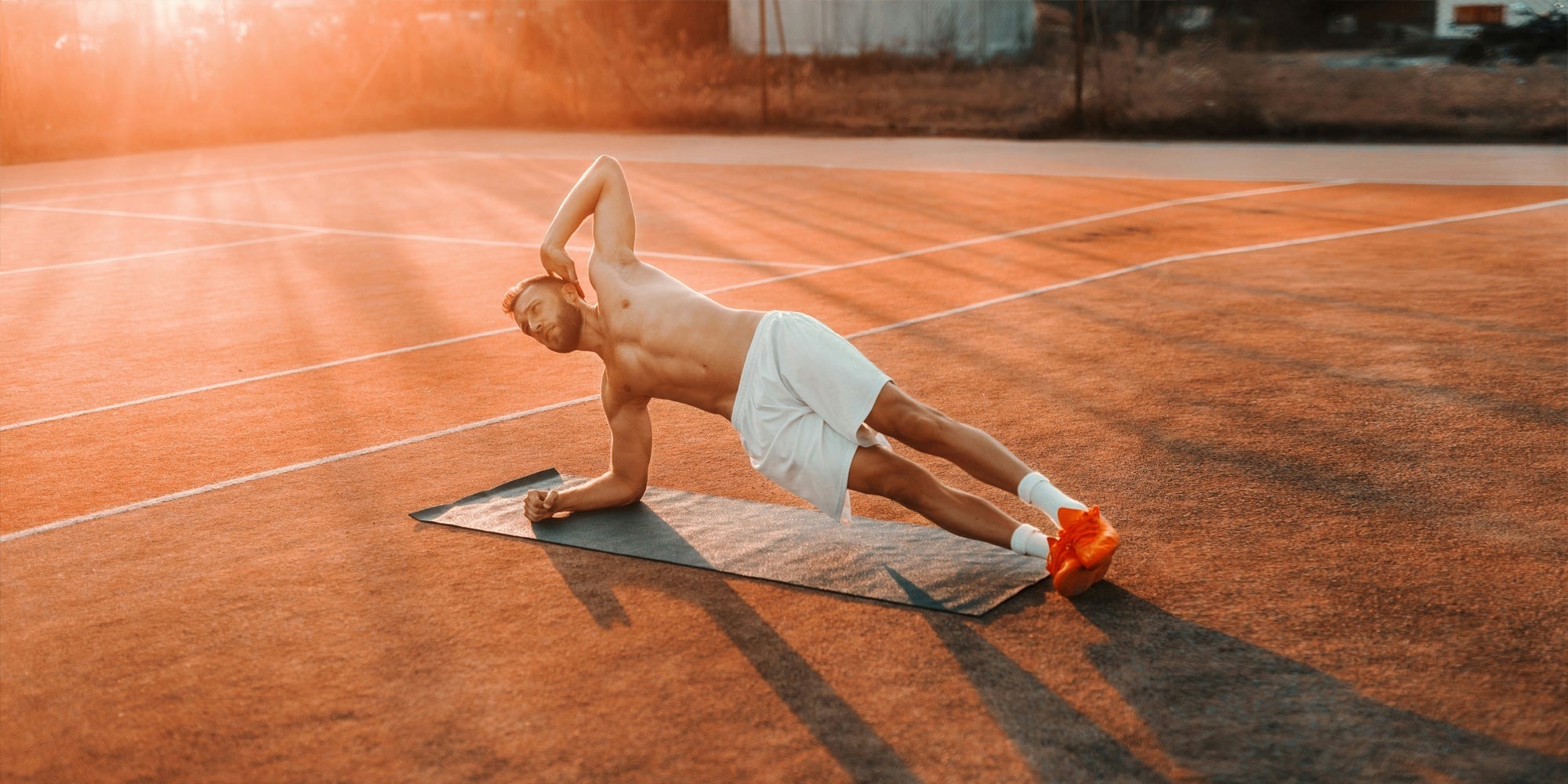 Man doing side plank on tennis court