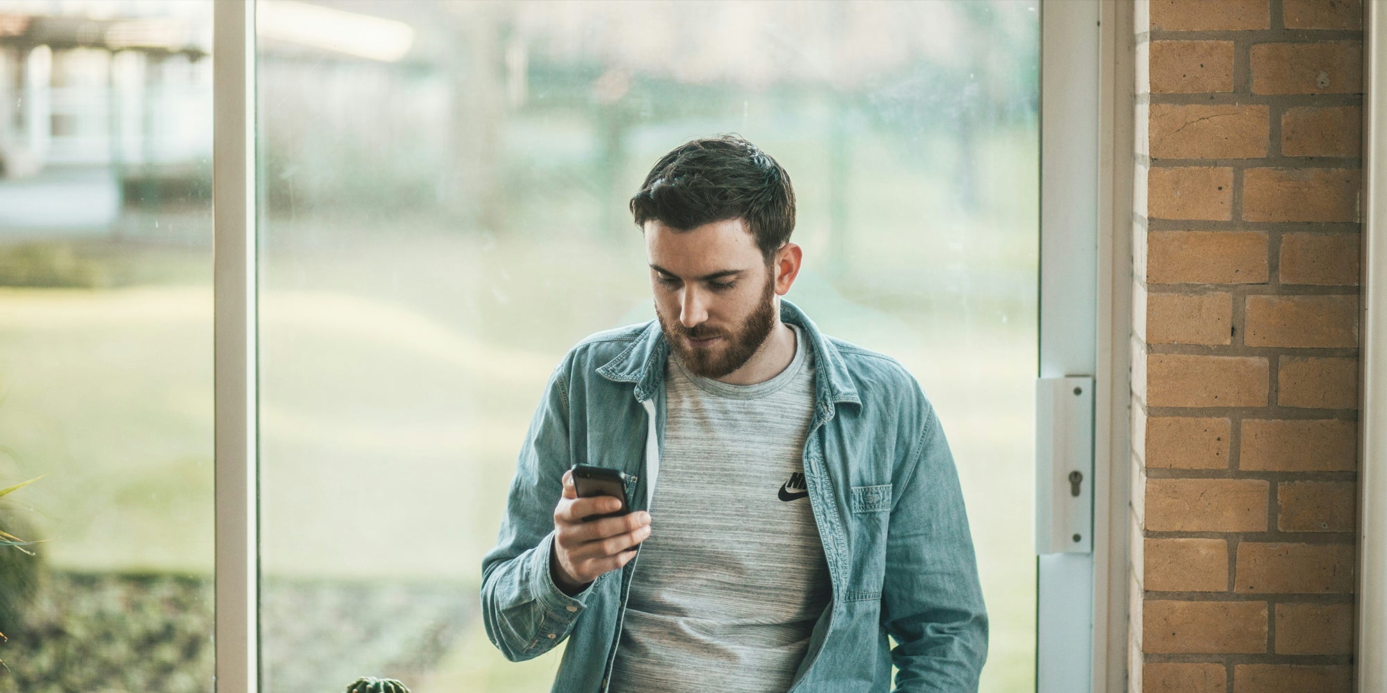 a man with a beard is looking at his cell phone