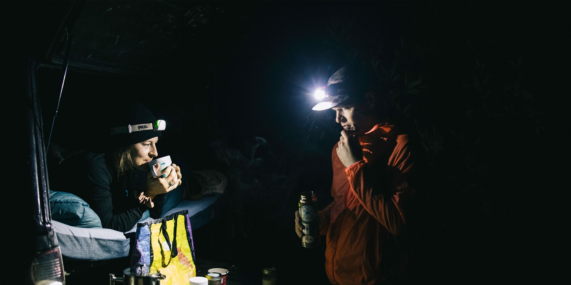 two people camping wearing head lamps